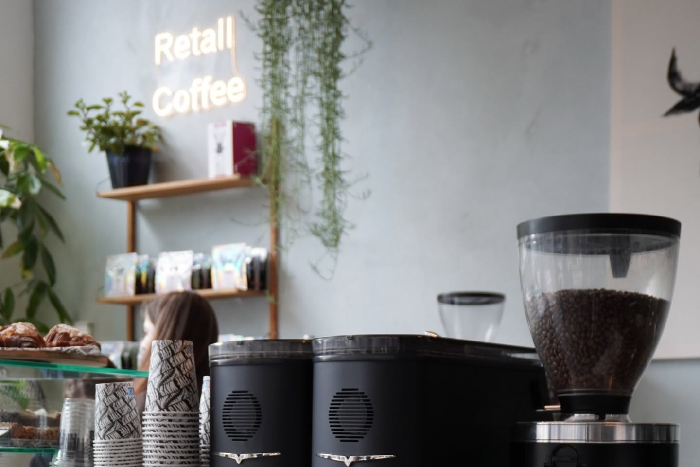The Five Ways counter with a Retail Coffee neon sign, retail bean shelf, twin grinders and a pastry case in the foreground