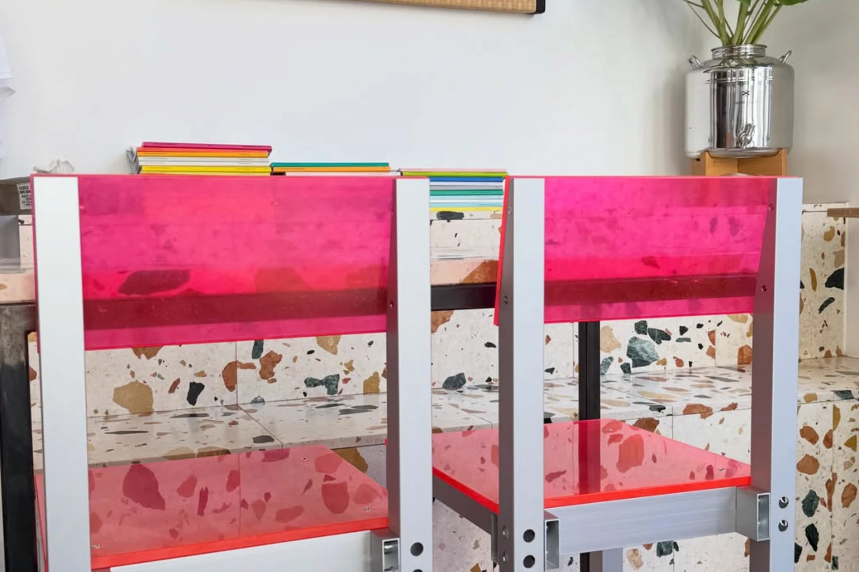 Two hot pink acrylic bar chairs against Toki's terrazzo tiled counter, sunflowers in a metal vase in the background