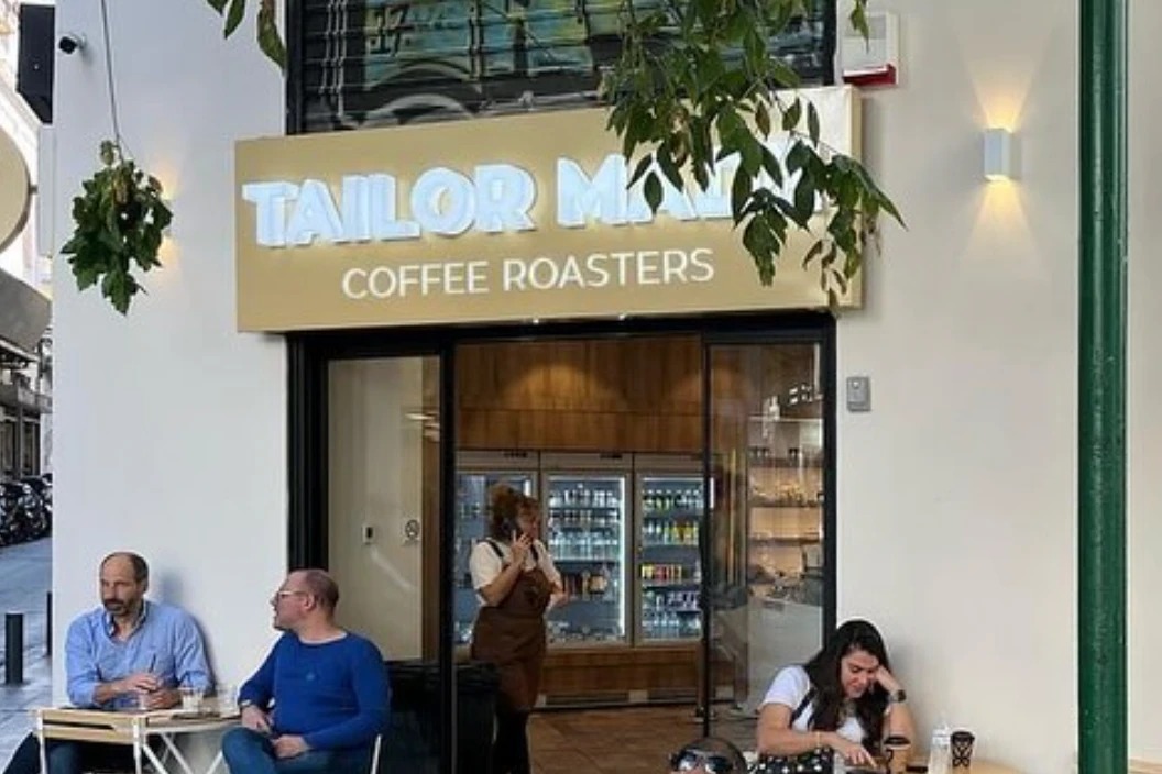 The Tailor Made Coffee Roasters storefront sign above the entrance, with customers seated at outdoor tables out front