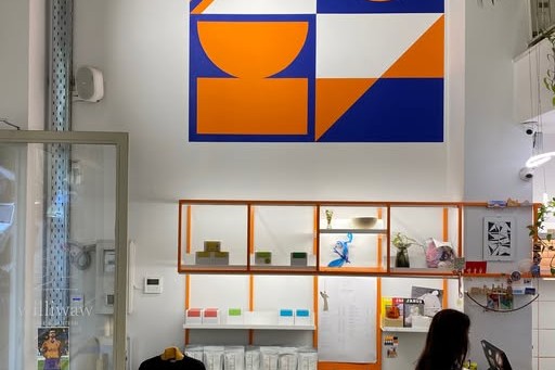 The orange and blue geometric mural above open shelving at Williwaw, with a staff member working the counter below