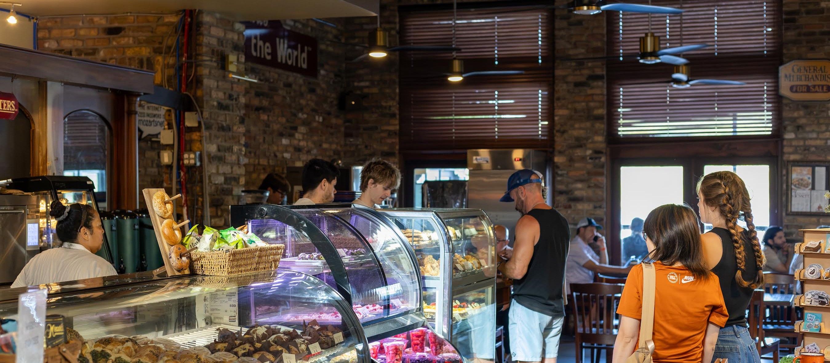 The pastry case and brick interior at Mozart's Coffee Roasters, customers ordering at the counter under hanging ceiling fans