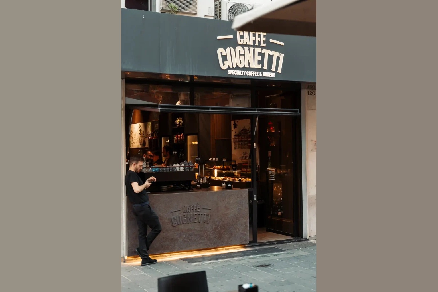 The storefront of Caffè Cognetti in Bari with its lit sign reading Caffè Cognetti Specialty Coffee and Bakery