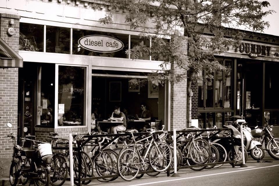 The black and white Diesel Cafe storefront sign in Davis Square, with a packed bike rack lining the sidewalk out front