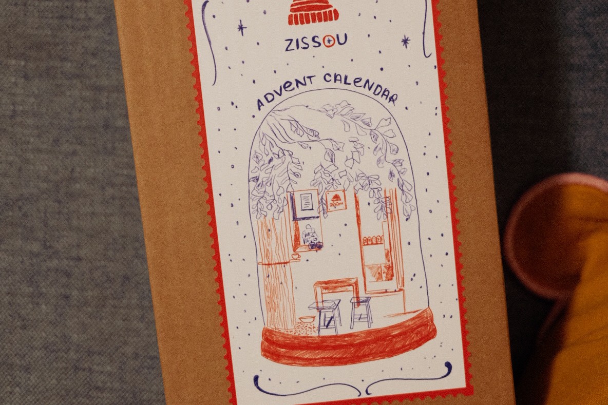 An illustrated Zissou Coffee Shop advent calendar box showing a hand drawn scene of the counter and seating