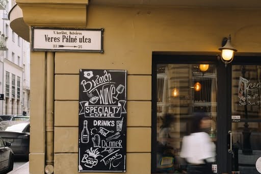 The corner storefront of DoubleShot with the Veres Pálné utca street sign and a chalkboard menu on the wall