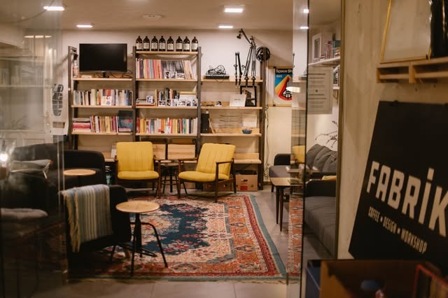 The lounge area at Fabrik with bookshelves, yellow armchairs, and the FABRIK signage on the glass door