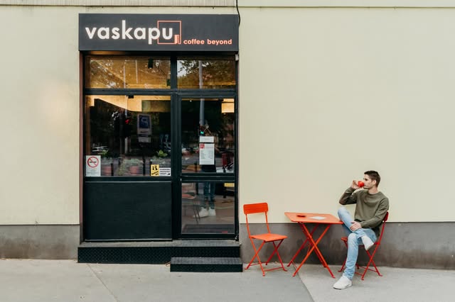 The Vaskapu, Coffee Beyond storefront sign on Haller utca, red bistro table and chairs set outside