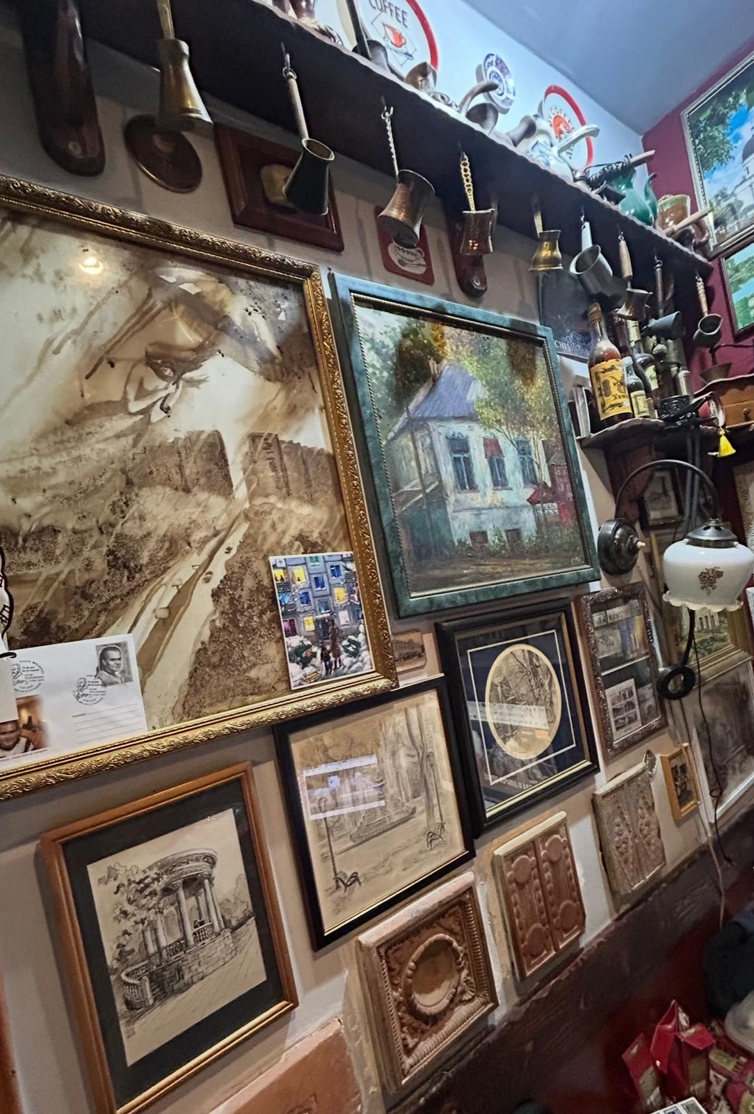 A wall of antique coffee grinders and framed pictures at CoffeeMolka's coffee museum interior