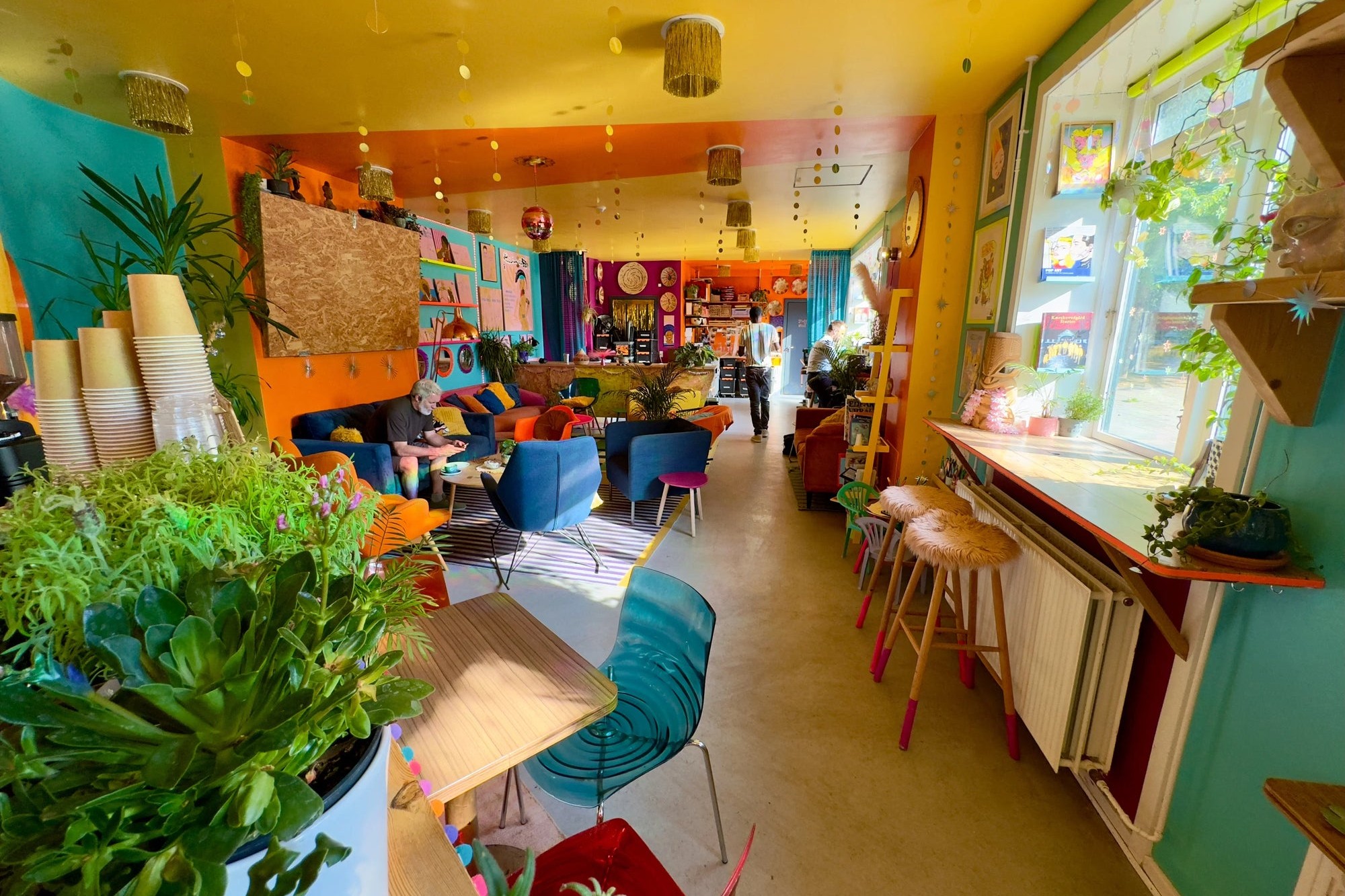 The maximalist, plant filled interior of Impact Roasters' Langgade St. cafe, with velvet armchairs and a gold painted ceiling