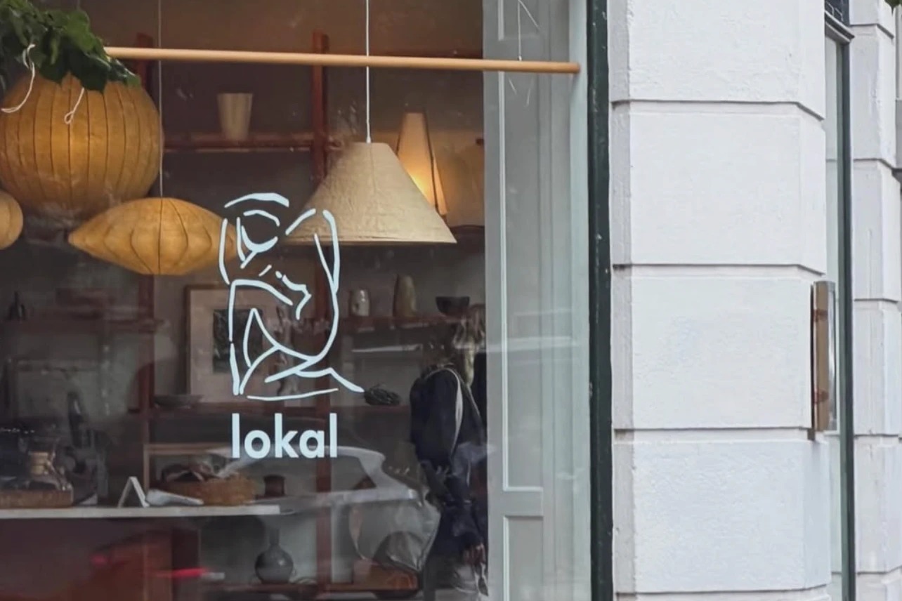 The lokal storefront window with its line drawn logo decal, paper lanterns overhead, and vintage ceramics visible on shelving inside