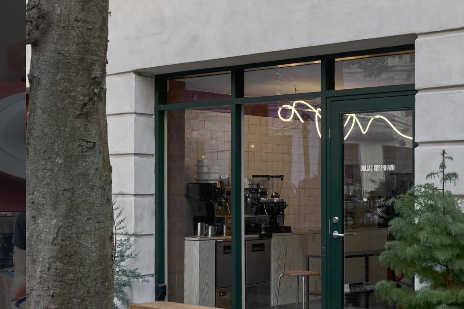 The Dallas, København storefront, a looping neon sign above the tiled counter with the espresso machine and a wooden bench out front