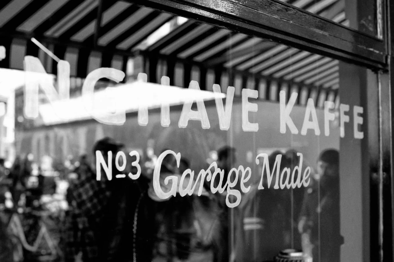 The hand painted Enghave Kaffe No3 Garage Made lettering on the shop's storefront window, shot in black and white