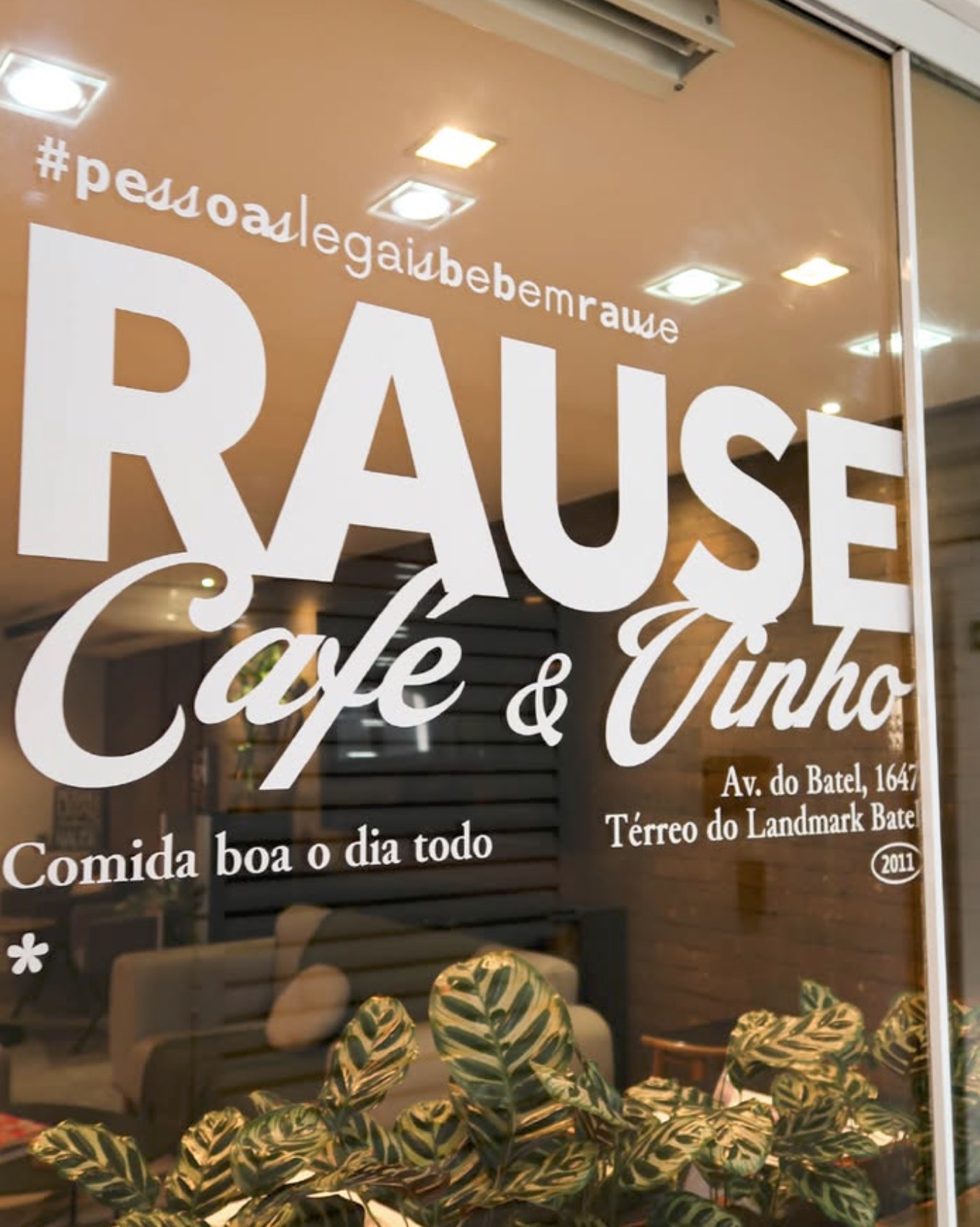 The Rause Café & Vinho name etched on the front window, the Batel storefront address and interior seating visible through the glass