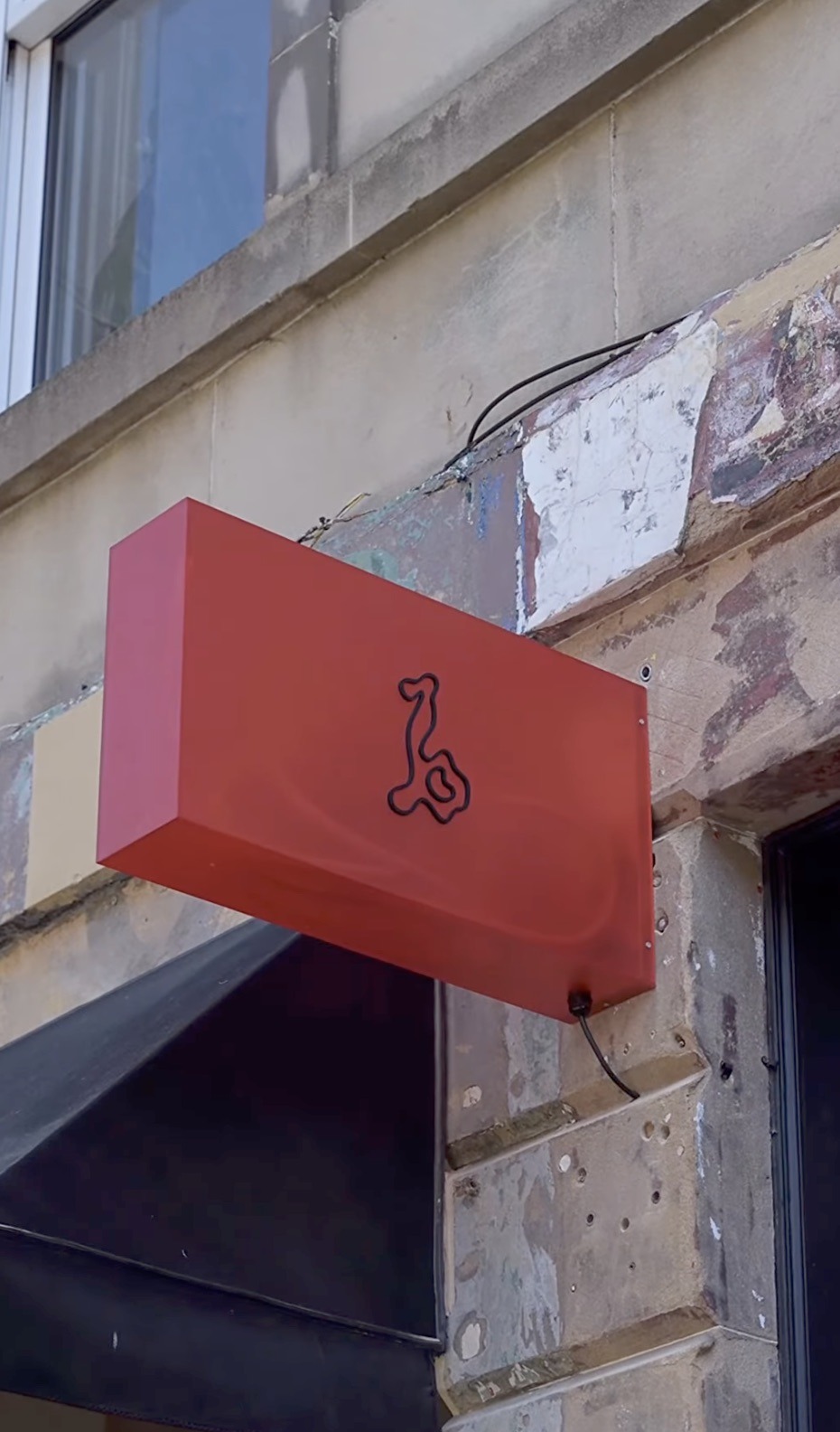 Beatnik's red sign with its musical note mark mounted on the weathered stone facade above the entrance