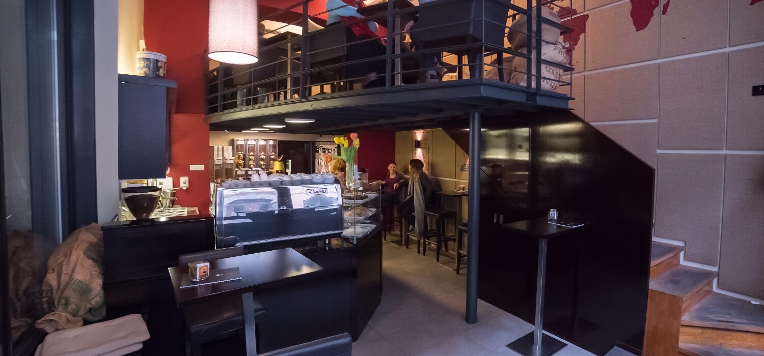 The two level interior of Cafetino in Ljubljana's old town, with a mezzanine seating area above the espresso counter
