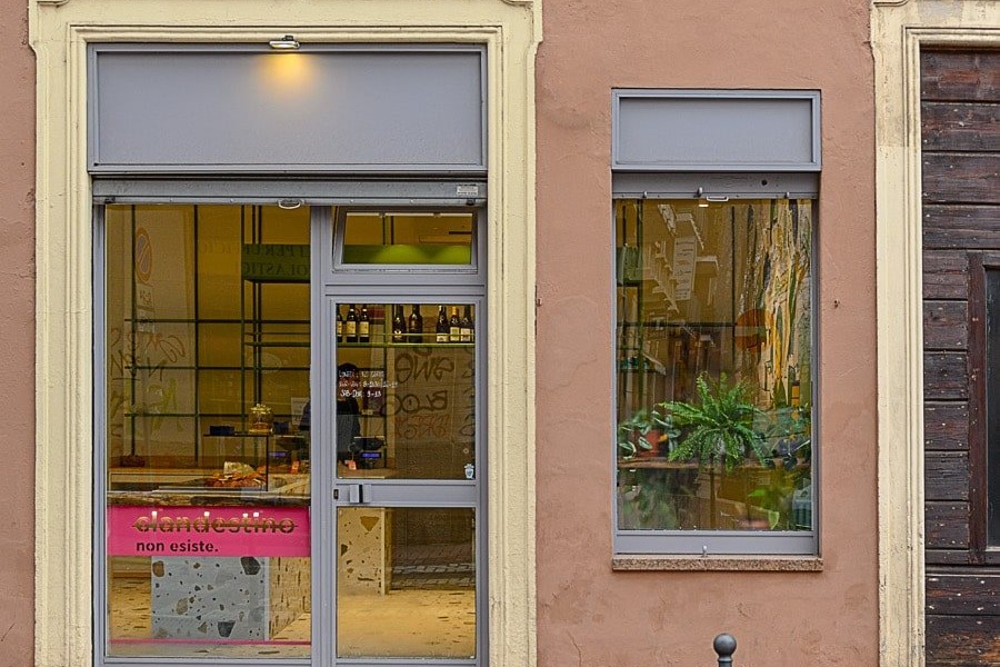 The Clandestino non esiste storefront window, a pink neon style sign reading clandestino non esiste beside the terrazzo counter