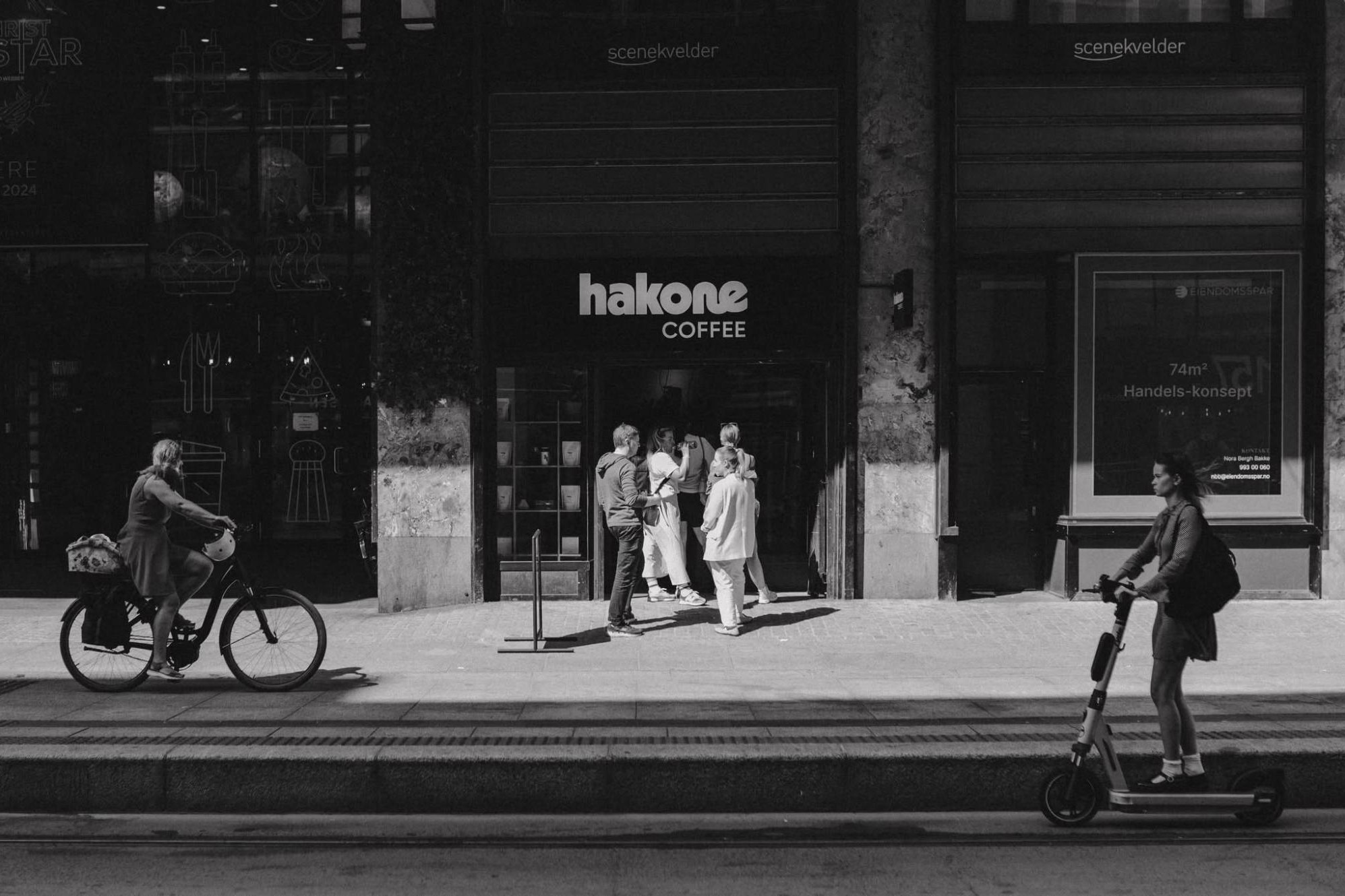 Black and white street view of the Hakone Coffee storefront on Storgata, with customers gathered at the entrance beneath the shop's sign