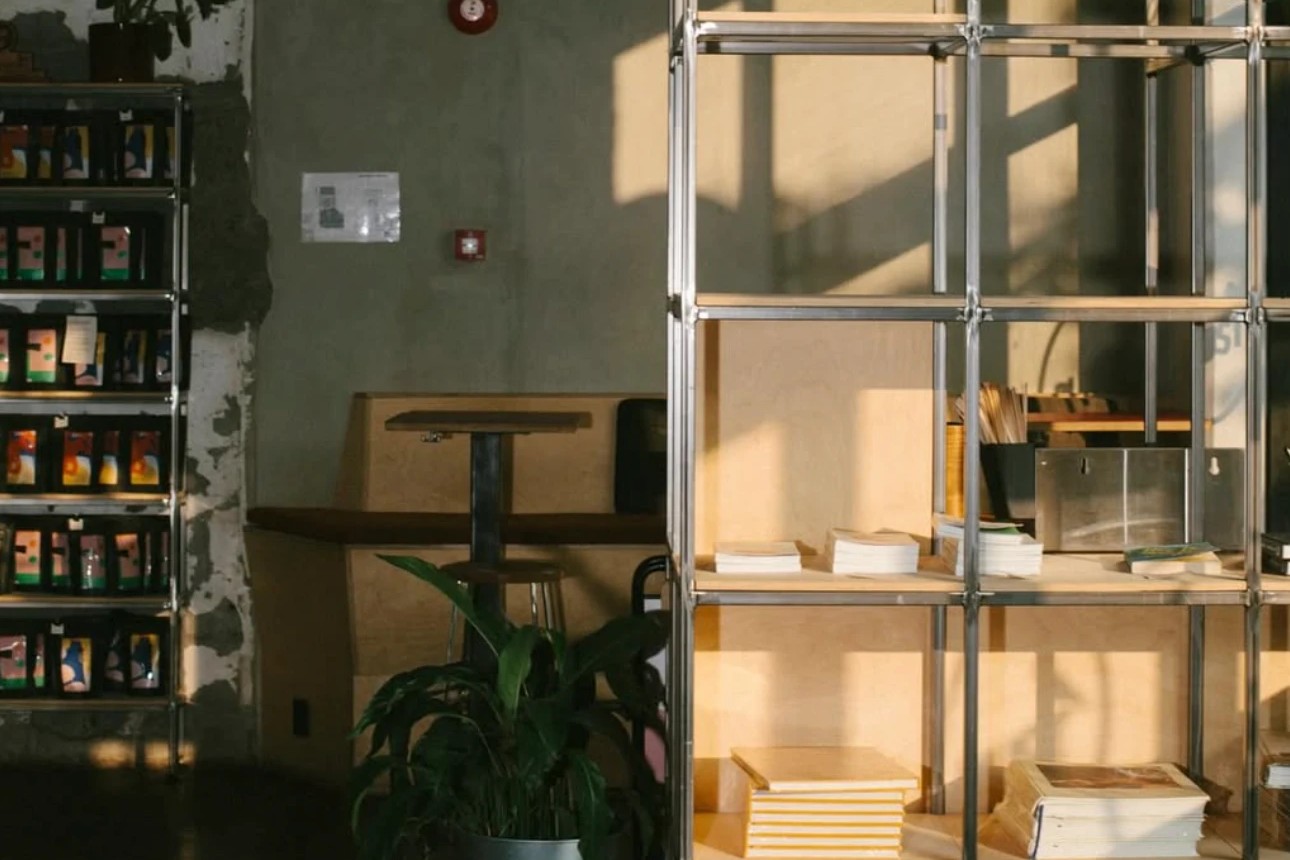 Sunlit interior of Pust with a retail shelf of bagged coffee on the left and a tall shelving unit stacked with books and recipe cards