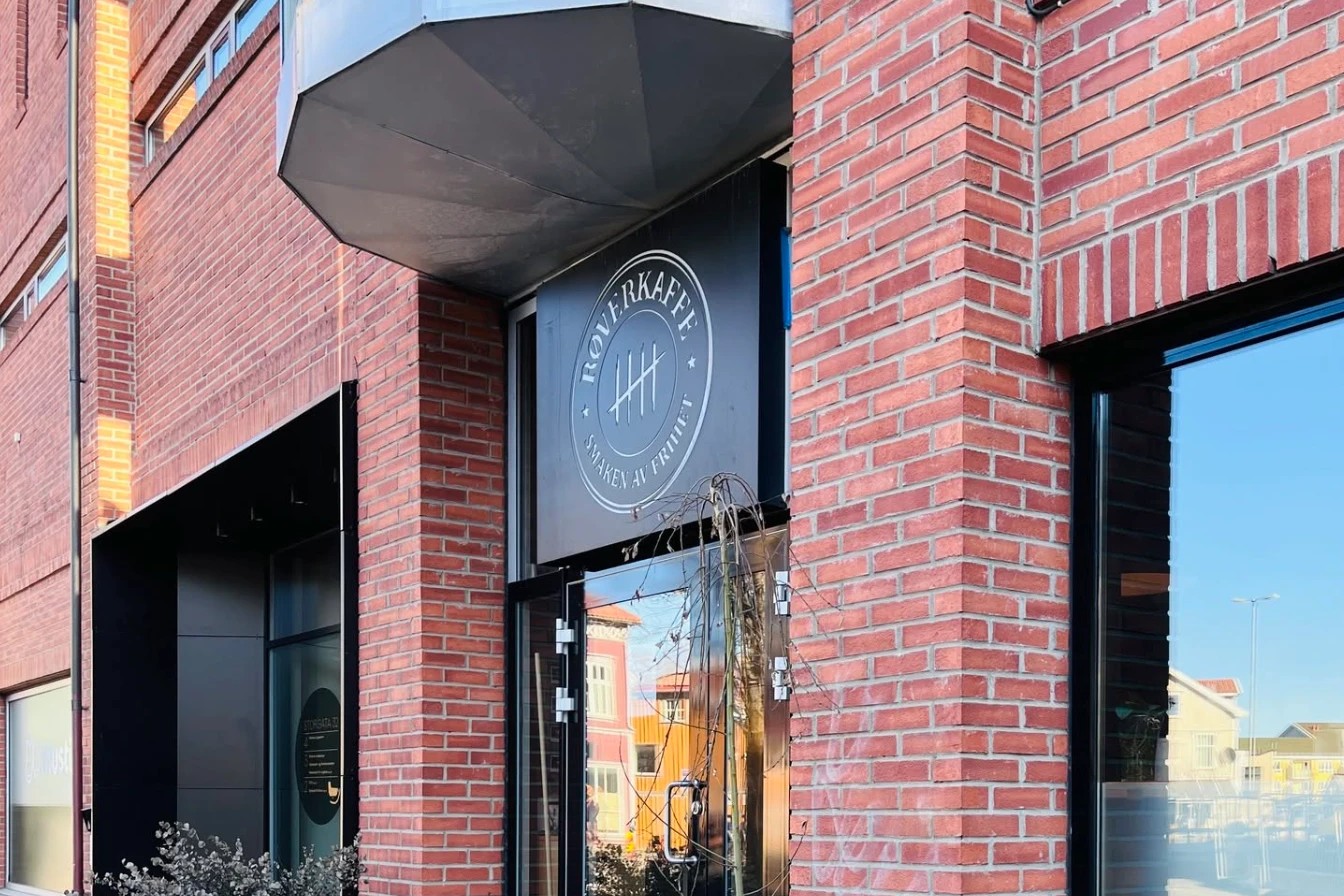The brick entrance of Røverkaffe with its round ROVERKAFFE, SMAKEN AV FRIHET tally mark logo mounted above the front door