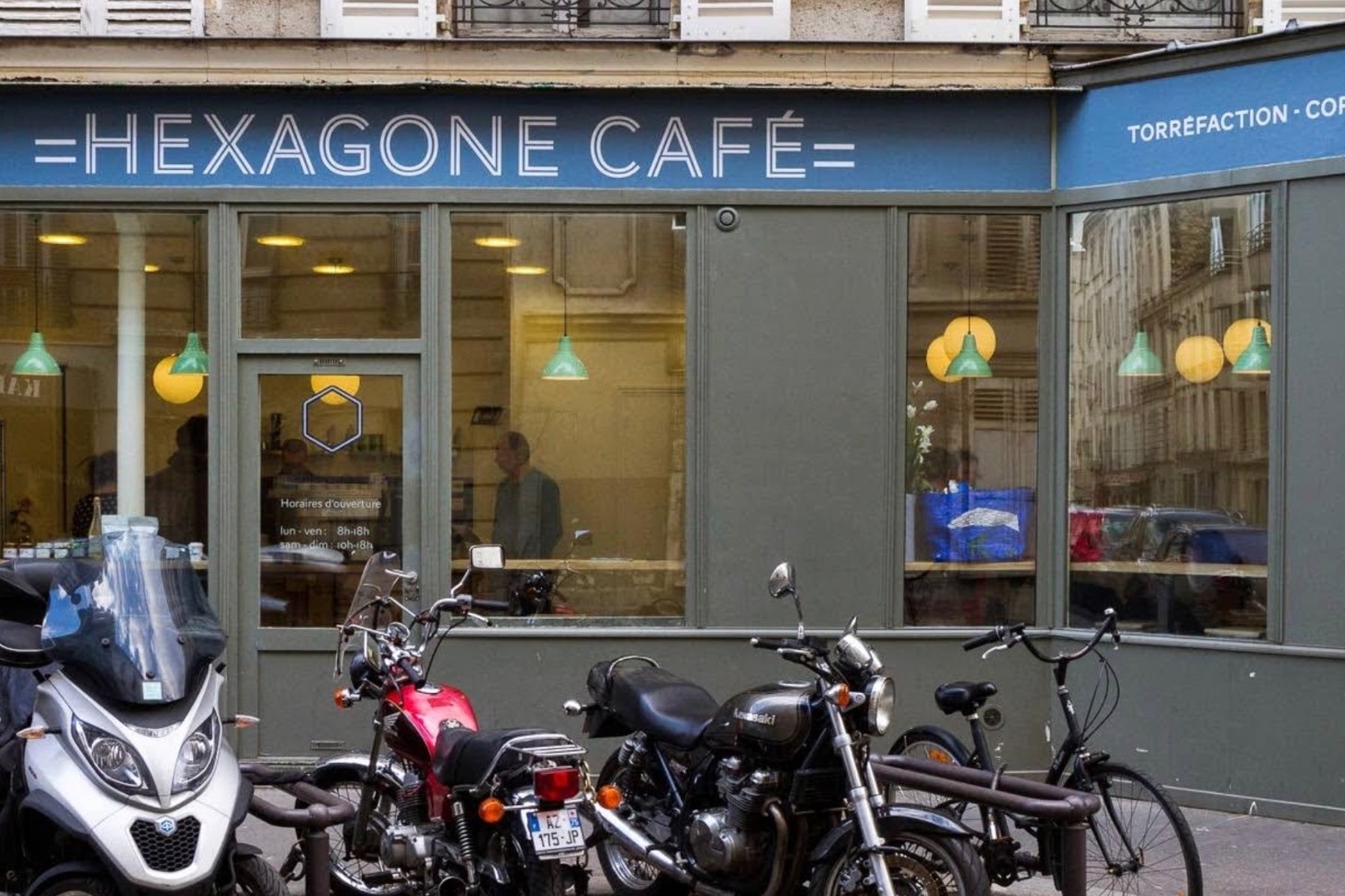 The blue HEXAGONE CAFÉ storefront on the corner of Rue du Château, torréfaction sign and green pendant lights visible through the windows