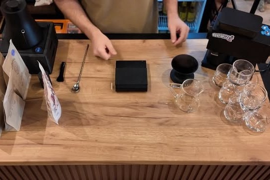 A barista working at the wooden counter at Turtles Specialty Coffee, glassware and brewing gear laid out in front of him