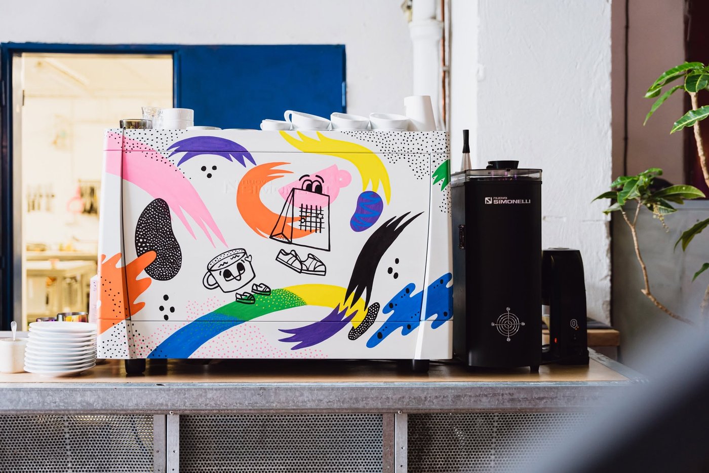 A hand painted espresso machine with colorful cartoon artwork on the counter at Industra Coffee