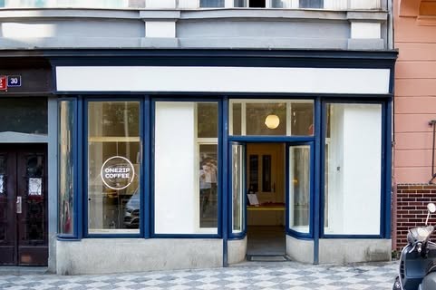The small blue framed storefront of Onesip Coffee on a quiet cobbled street in Stare Mesto