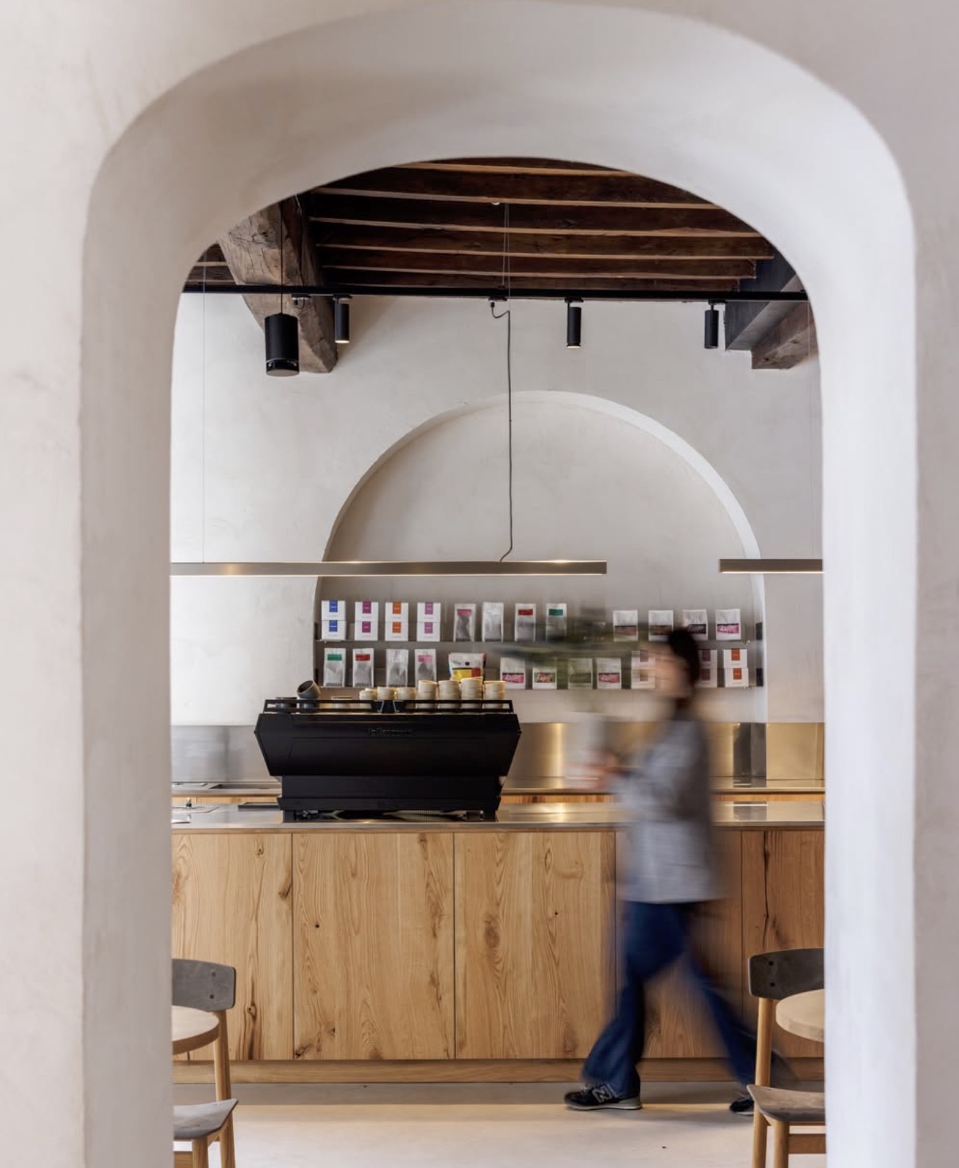 An arched, white-plastered doorway framing the espresso bar at Barnum Roma, retail coffee bags on the shelf behind