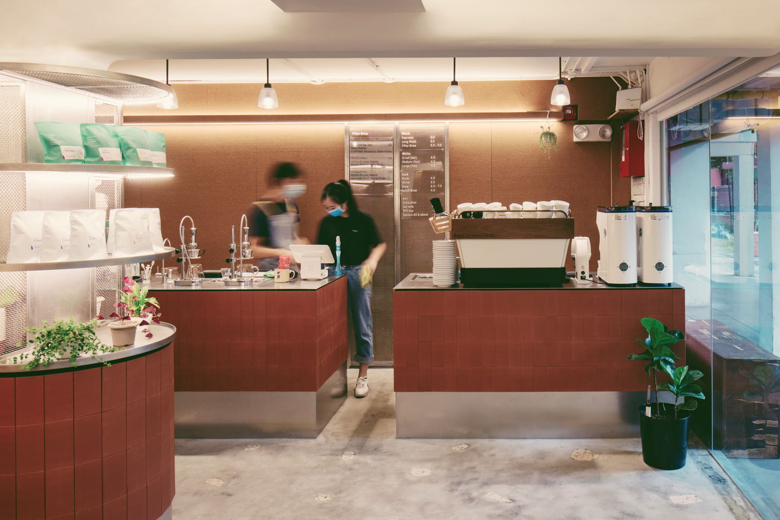 The red tiled coffee bar at Nylon Coffee Roasters with staff working behind the counter and retail bean bags on the shelf
