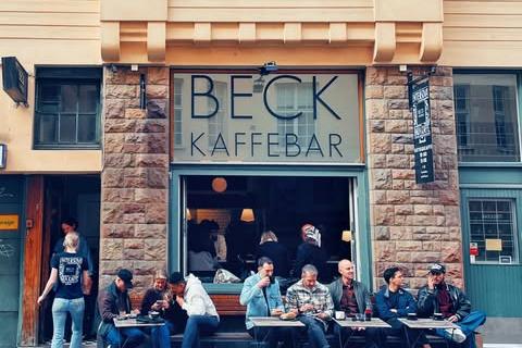 The BECK KAFFEBAR sign above the entrance on Tjarhovsgatan, with people seated at outdoor tables on the terrace below