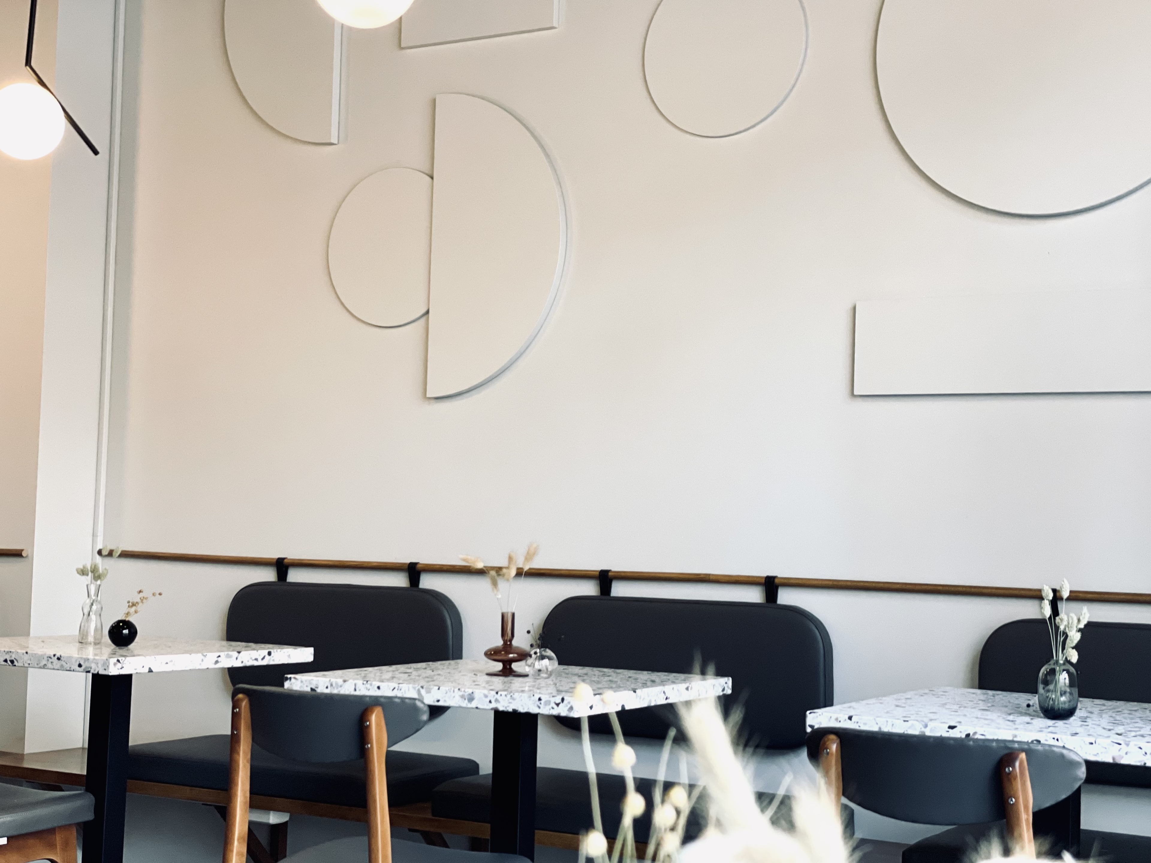 The black and white interior of Komet Cafe with terrazzo topped tables and moon shaped wall panels