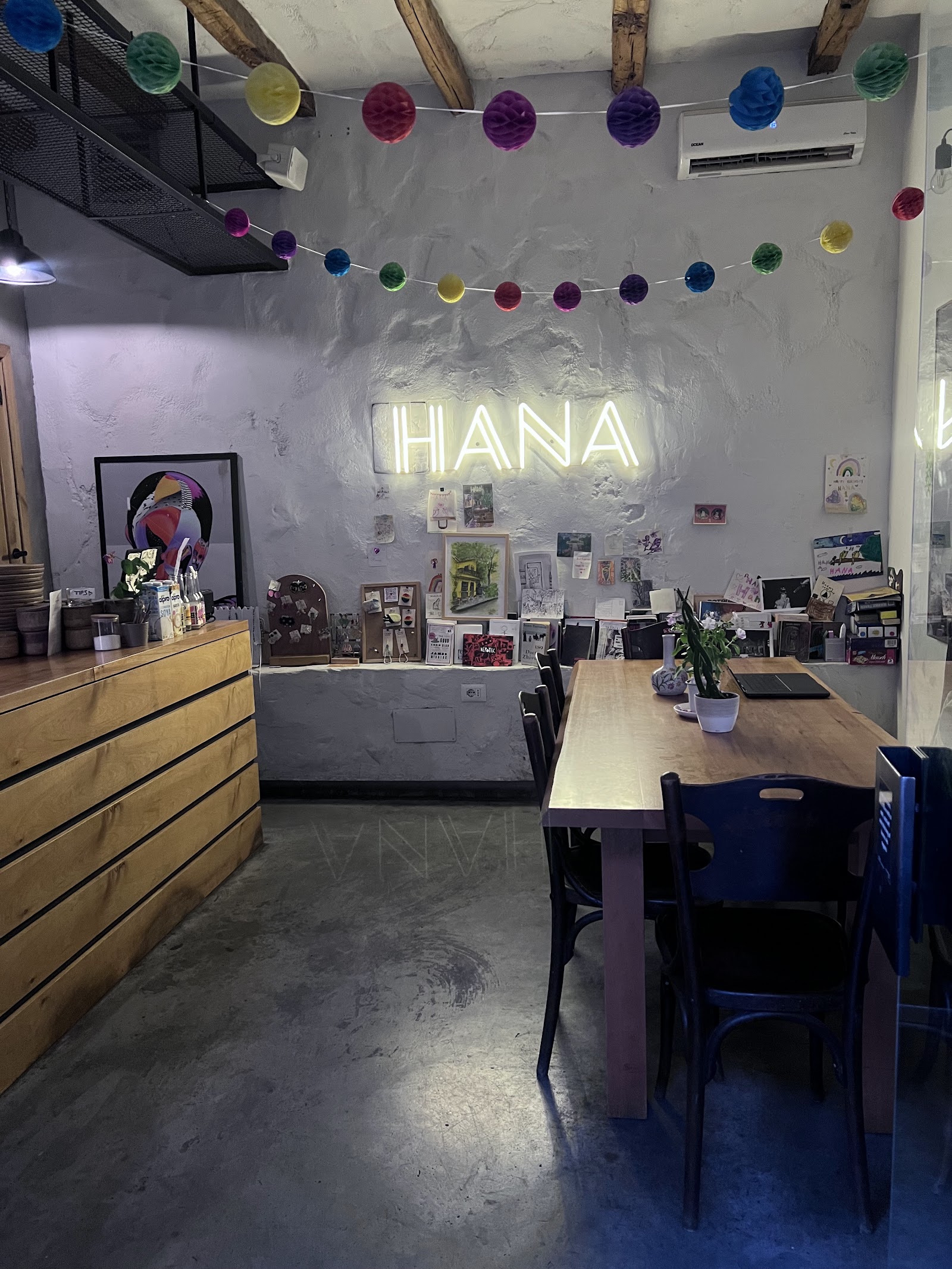 The wood slat HANA sign and plant filled interior of Hana Corner Cafe in Blloku