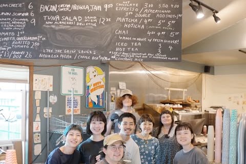 The Paddlers Coffee team standing at the counter below a hand chalked menu board of espresso drinks and sandwiches
