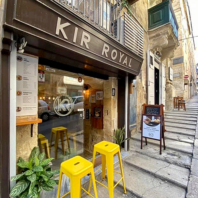 The KIR ROYAL storefront sign on a stone Valletta street with yellow stools out front