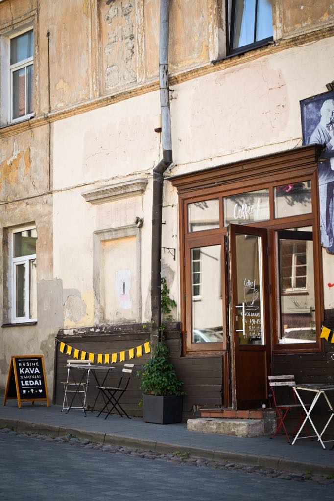 Coffee1's storefront on a quiet Uzupis street with small outdoor tables and folding chairs